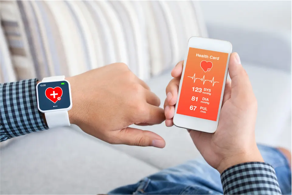 A man holding a smartwatch on his left hand a smartphone on his right